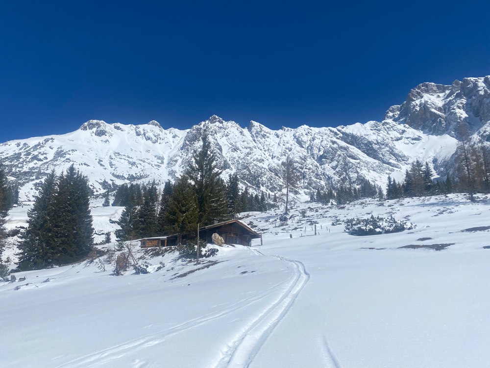 Silberbrunn im Winter: die Hütte auf der verschneiten Alm, dahinter die Berge des Hochkönigs